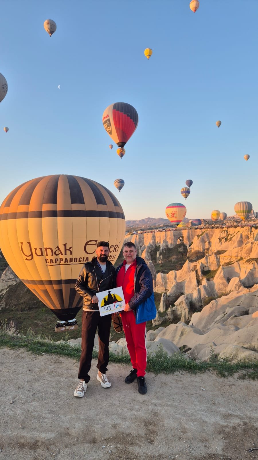Guests with the 123 Trip sign as balloons rise over the valley